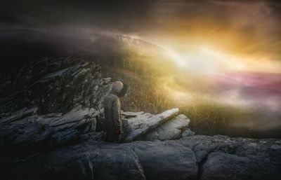 Female hiker standing on mountain against sky during sunset