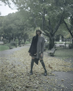 Full length of young woman standing against trees