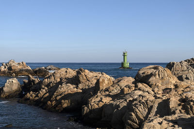 Lighthouse by sea against sky