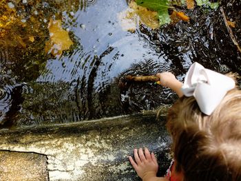 Cropped image of girl holding stick in pond at fairbury city park