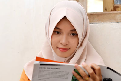 Portrait of a smiling young woman against wall