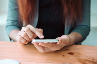 Midsection of woman holding hands on table