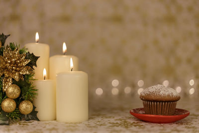 Close-up of christmas decoration with candles and cupcake on table