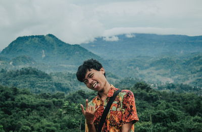 Young man looking at mountains against sky