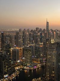 Illuminated buildings in city against sky during sunset
