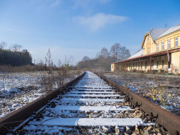 Snow covered railroad tracks against sky during winter