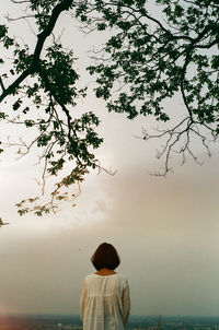 Rear view of woman standing by sea against sky