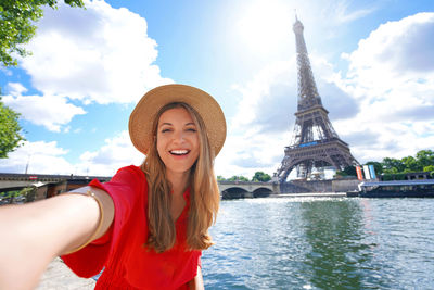 Young tourist woman making selfie photo with eiffel tower on the background in sunny day in paris