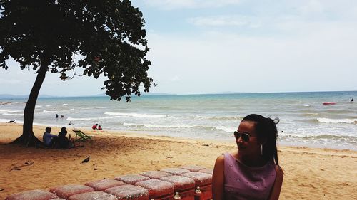 Young woman on beach against sky