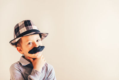 Portrait of boy wearing hat against wall