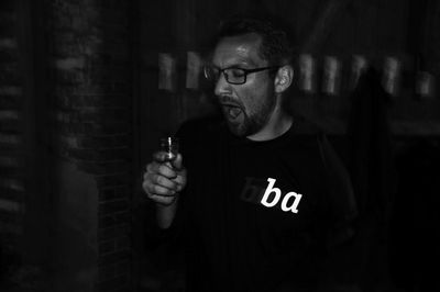 Young man yawning while holding shot glass during party