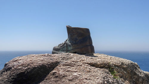 Rock formation by sea against clear blue sky