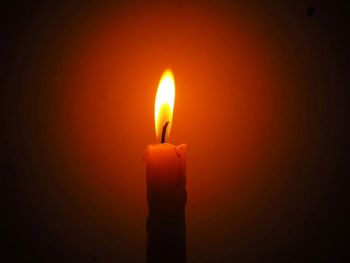 Close-up of lit candle against black background