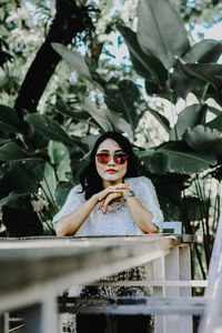 Portrait of young woman standing against plants