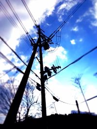 Low angle view of electricity pylon against cloudy sky