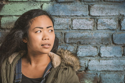 Portrait of beautiful young woman against wall