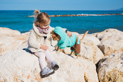 Side view of woman sitting on rock at beach