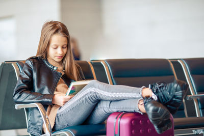 Girl using reading book while sitting at airport