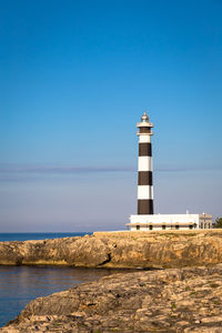 Lighthouse by sea against sky