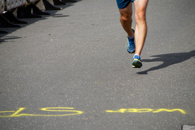 Low section of man running on footpath during marathon