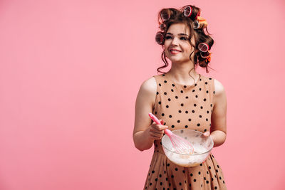 Woman holding pink flower against gray background