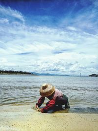 Fisherman collecting seashells on shore against sky