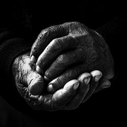 Close-up of cropped hand over black background