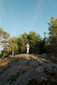 Woman standing on rock against sky