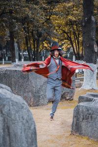 Man cosplaying mad hatter spinning on grass around gaint stones