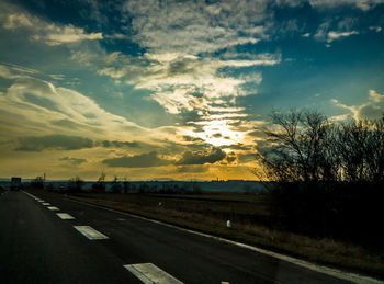 Road passing through landscape against cloudy sky