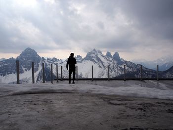 Man walking on snowcapped mountain against sky