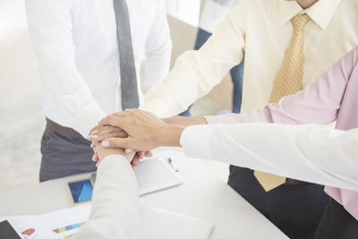 Cropped image of colleagues stacking hands in office