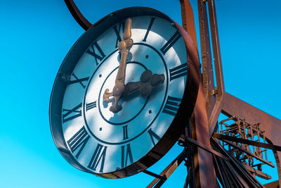 Low angle view of clock against clear blue sky