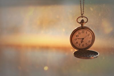 Close-up of pocket watch hanging against blurred background