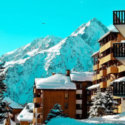 Snow covered houses by mountain against sky