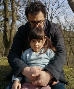  father haging daughter sitting outdoors