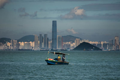 Boat sailing on sea against buildings in city