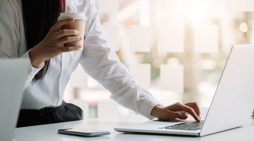 Midsection of man using laptop on table