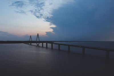Bridge over sea against sky during sunset