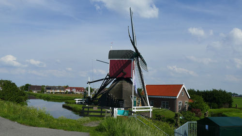 Traditional windmill by building against sky