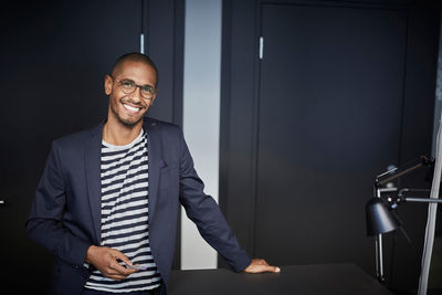 Portrait of confident male entrepreneur standing in creative office