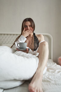 Young woman drinking coffee cup on bed at home