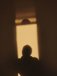 Rear view of silhouette man standing against wall