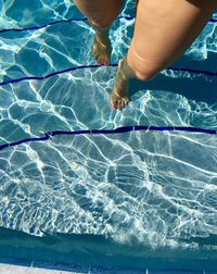 Low section of woman walking in swimming pool