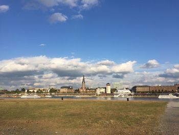 Distant view of factory against cloudy sky