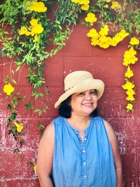 Portrait of smiling woman standing against yellow wall