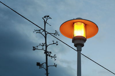 Low angle view of illuminated street light against cloudy sky at dusk
