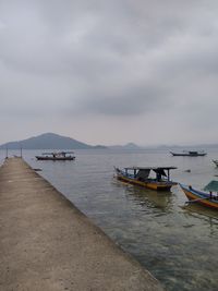 Boats moored in sea against sky