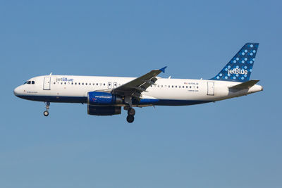 Low angle view of airplane against clear blue sky