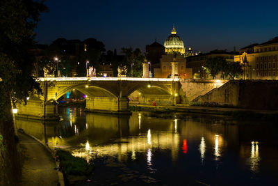 Illuminated bridge over river in city against sky at night